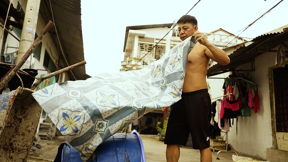 Ông Trần Văn Hòa đang trải bạt phủ lại cuộn dây dẫn nước