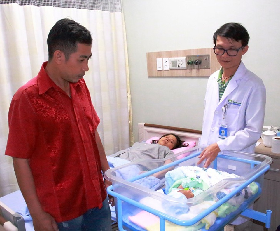 Anh K. (bên trái) cùng bác sĩ Tâm bên cháu bé vừa chào đời sau hành trình 5 tháng đầy trắc trở.