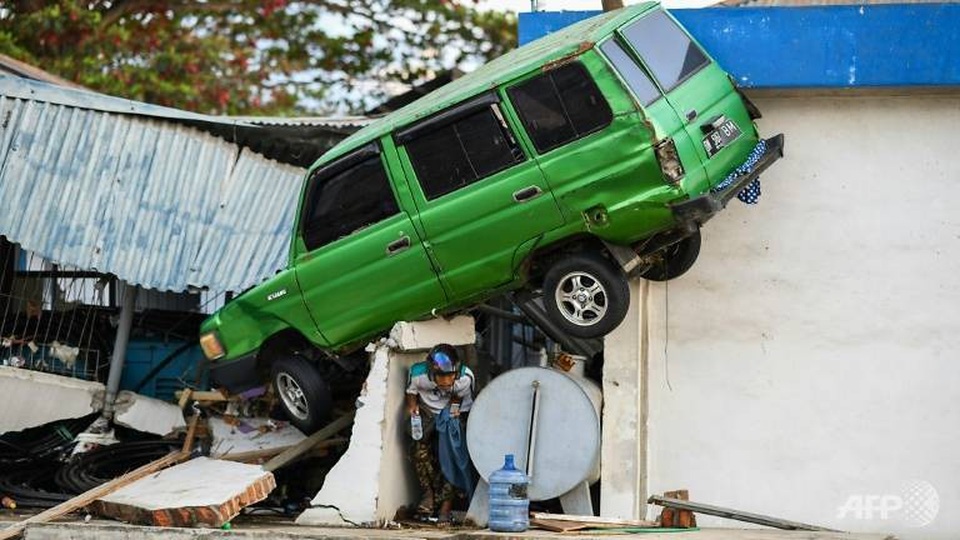 Động đất/sóng thần tại Indonesia: 34 sinh viên bị chôn vùi, 52 người mất tích - 4 Xe ô tô bị cuốn bay vào nhà dân sau thảm họa tự nhiên (Ảnh: AFP)