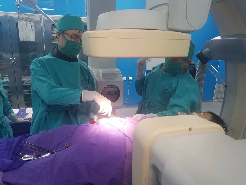 Qua hệ thống DSA, lấy dị vật kim khâu 2,5mm cho trẻ 11 tuổi - 1 Kíp phẫu thuật bệnh viện Sản Nhi đang lấy dị vật tại tay của trẻ (ảnh QTV)