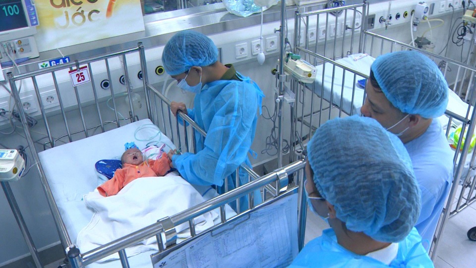 Giây phút Thành Công nắm lấy bàn tay nhỏ xíu của em trai đang nằm trên giường bệnh.