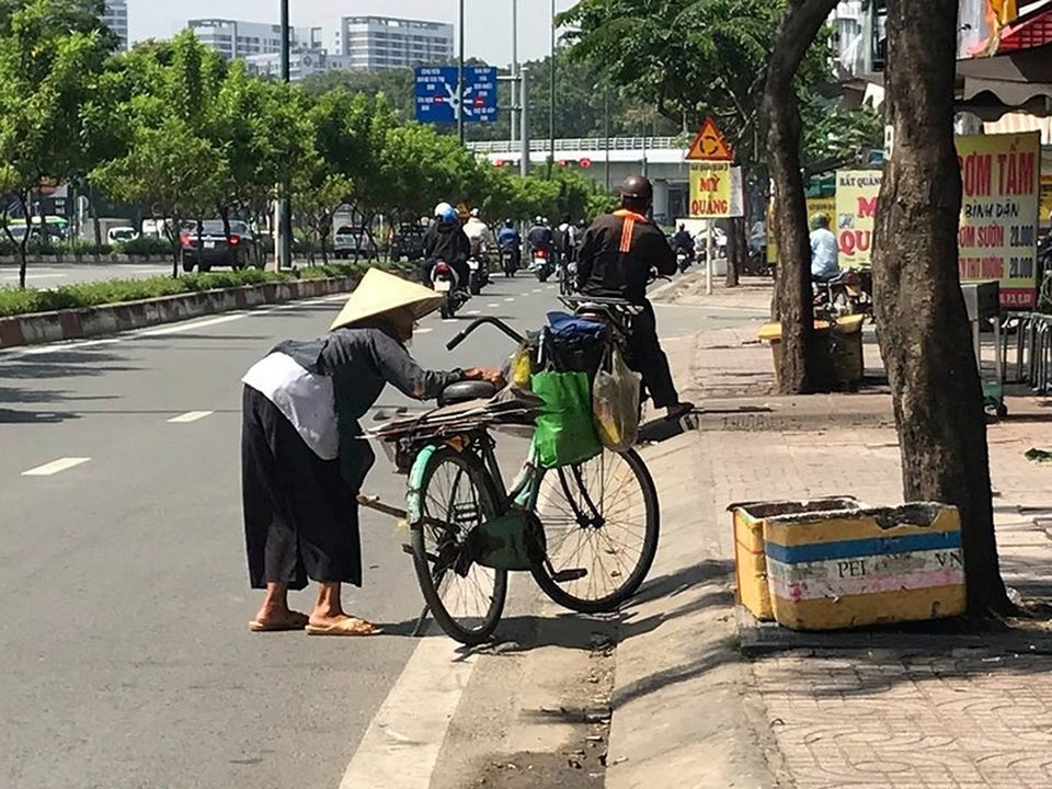 Bà già ve chai liêu xiêu giữa dòng đời bất tận - 1 Giữa trưa nắng đổ, cụ già còng lưng với chiếc xe đạp cũ đi kiếm ve chai. Ảnh: VIỆT HOA