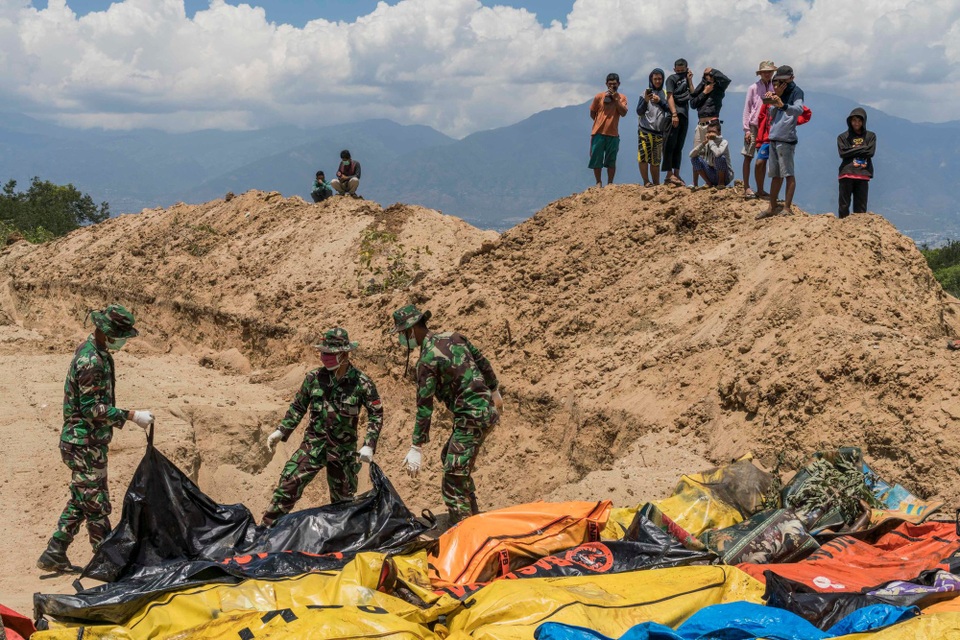 Các binh sĩ kéo túi đựng thi thể các nạn nhân tại ngôi mộ tập thể ở ngoại ô Palu. (Ảnh: New York Times)