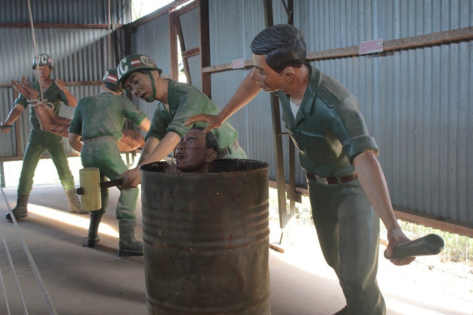 Mô hình tái hiện màn tra tấn bằng cách tống tù nhân vào thùng phuy đầy nước, một tên ấn đầu xuống, một tên dùng vồ đập mạnh vào thành phuy. Tù nhân vừa sặc nước, vừa như vỡ tai, đầy đau đớn.