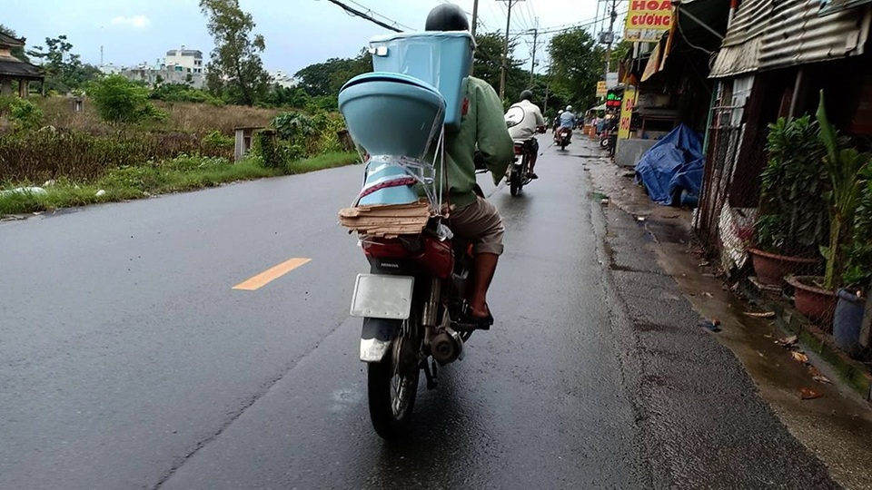Lạc vào “thánh địa” đồ nội thất cũ ở Sài thành - 8 Một khách hàng đang vận chuyển chiếc bồn cầu vừa chọn được, hình ảnh khá quen thuộc trên cung đường này