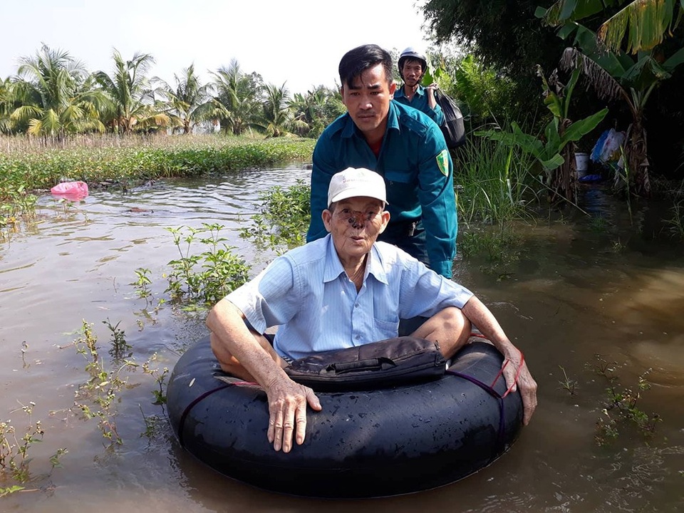 Hàng chục hộ dân khốn khổ vì triều cường, nước lũ - 1 Lực lượng dân phòng địa phương di dời người già, trẻ nhỏ ra khỏi nơi ngập nước