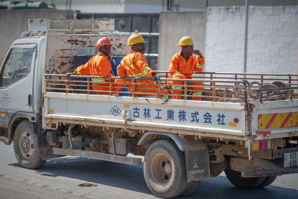 Lợi nhuận và cạm bẫy của những khoản đầu tư Trung Quốc vào châu Phi - 1 Những công nhân Zambia đi làm trên chiếc xe tải có dòng chữ Trung Quốc. (Nguồn: Siobhan Heanue)