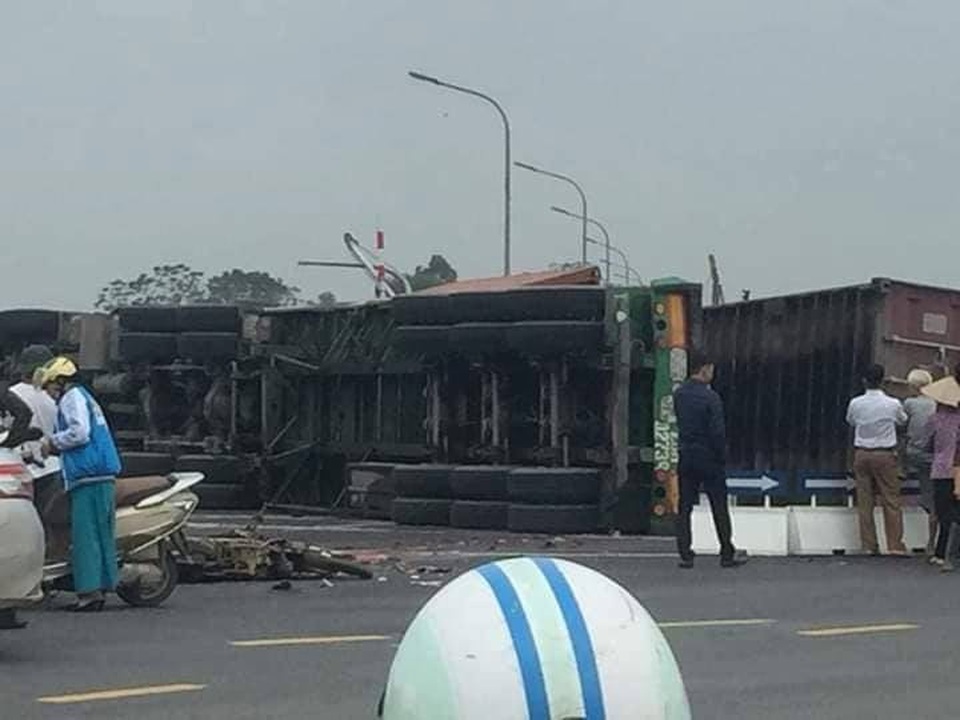Hà Nội: Xe container lật nghiêng, 2 người đi xe máy bị đè tử vong - 1 Xe container lật nghiêng đè lên 2 nạn nhân sau cú va chạm (Ảnh: Sa Ngân).