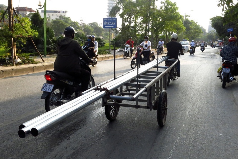 Xe chở sắt thép "siêu cồng kềnh" hoành hành ở Hà Nội - 1
Một chiếc xe kéo tự chế đang chở những ống thép dài tới 5-6m với phần đuôi thò hẳn ra ngoài. Đầu những ống thép này cao ngang tầm bụng, là những vật cực kỳ nguy hiểm nếu vô ý va phải khi di chuyển trên đường phố.