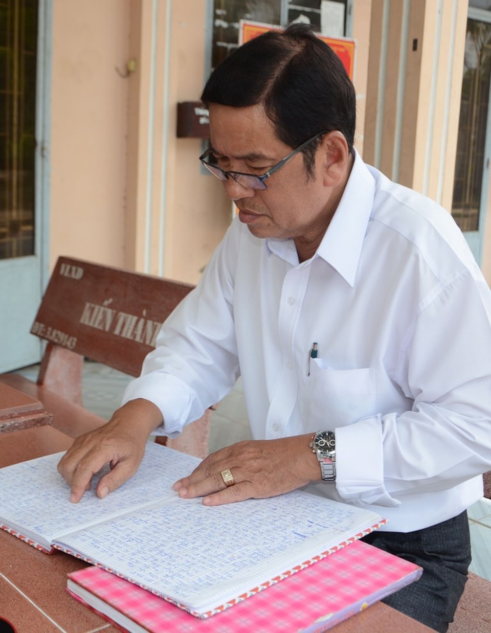 Ông Ngô Thanh Liêm bên cuốn sổ khổ A4 ghi chi tiết lý lịch người nghèo, hoàn cảnh cơ nhỡ khi chết mà chính ông và Hội Chữ thập đỏ thị trấn Vĩnh Thuận hỗ trợ.