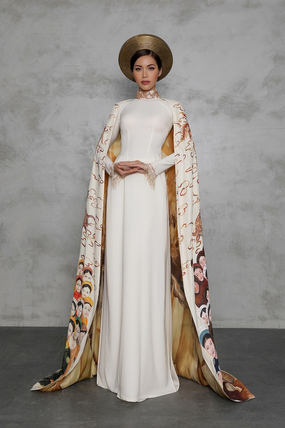 Bộ áo dài này gồm hai phần, là áo dài cổ cao - khăn đóng trong với phông dáng truyền thống cùng phần áo choàng bên ngoài được làm tỉ mỉ và sang trọng. Bộ áo dài trong được làm bằng chất liệu silk lụa, đính kết nhẹ nhàng bởi những viên đá quý cổ thạch thời xưa (đá Agte và đá Opal) không quá lấp lánh nhưng rất giá trị và tinh tế.