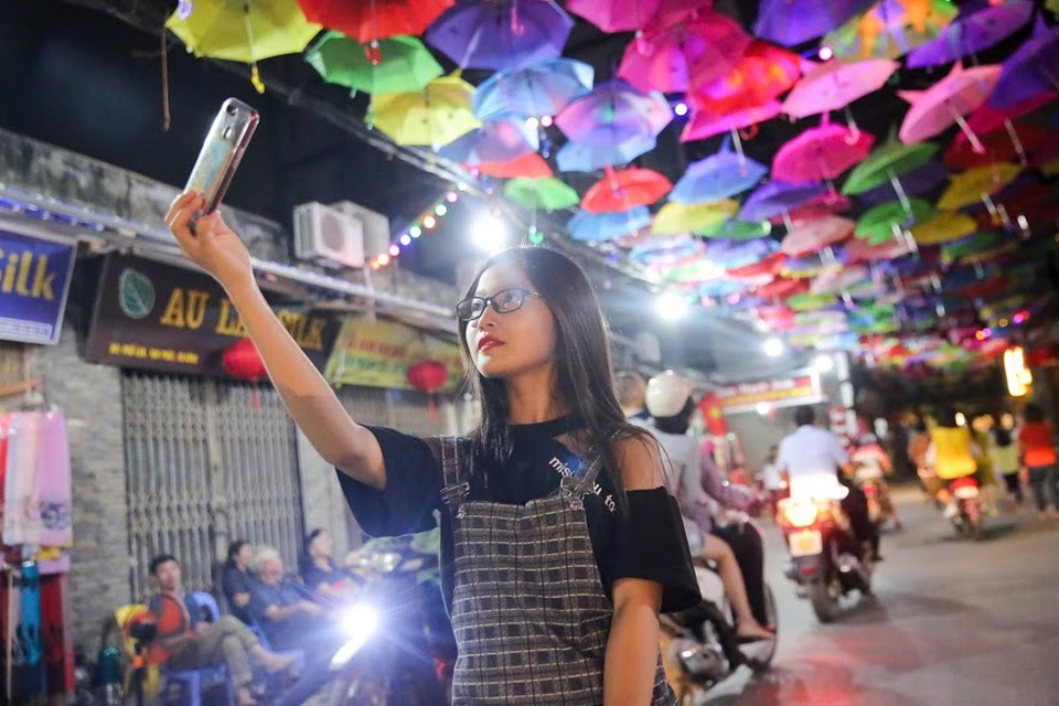 Một bạn trẻ thích thú tạo dáng dưới con đường ô rực rỡ sắc màu