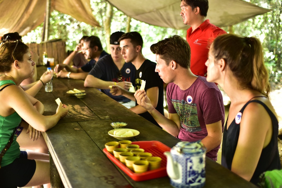 Thành phố Hồ Chí Minh đón khách quốc tế thứ 7 triệu - 5 Các tour đặc biệt sẽ đưa du khách trong và ngoài nước đến với các địa điểm gắn liền với lịch sử 320 năm của thành phố như: Bưu điện Thành phố, Nhà thờ Đức Bà, Bảo tàng Thành phố, Chợ Bình Tây, Bảo tàng Chứng tích Chiến tranh, Lăng Lê Văn Duyệt, Chùa Bà Thiên Hậu, Chùa Ngọc Hoàng, Địa đạo Củ Chi, Cần Giờ… Trong ảnh: du khách đang thưởng thức món khoai mỳ ở địa đạo Củ Chi
