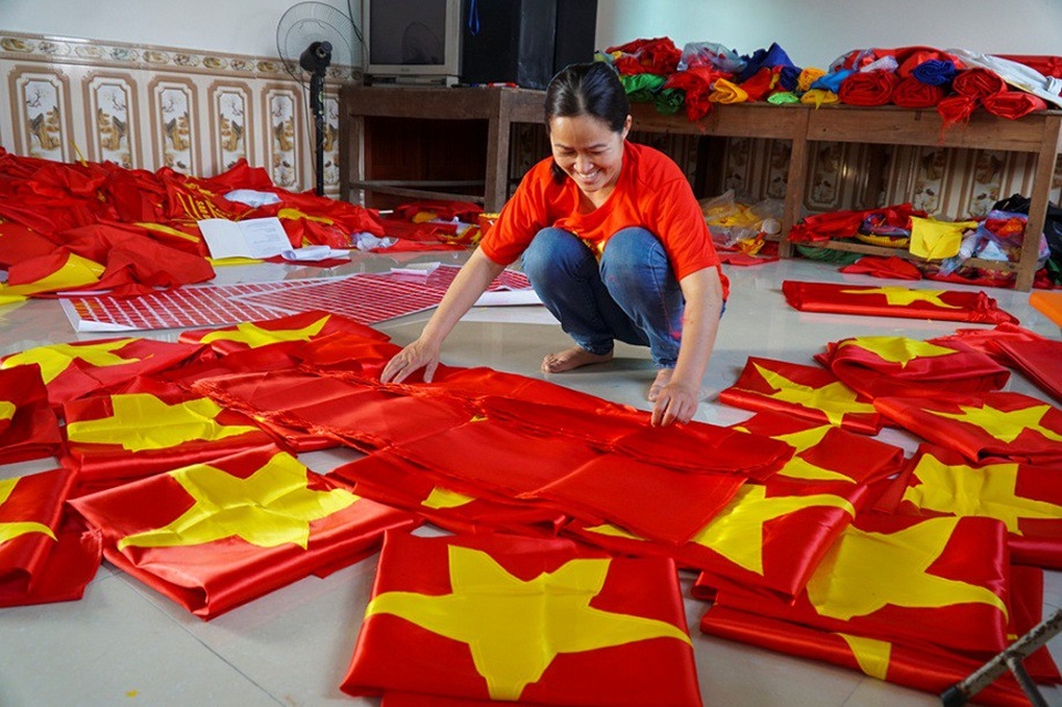 
Cơ sở của chị Vương Thị Nhung ở thôn Từ Vân (xã Lê Lợi) chuyên làm cờ Tổ quốc và các loại băng rôn, cờ vẫy, áo cờ đỏ sao vàng ... những ngày gần đây tất bật cả ngày lẫn đêm, huy động nhiều nhân công làm việc để phục vụ nhu cầu của người hâm mộ bóng đá khắp cả nước.
