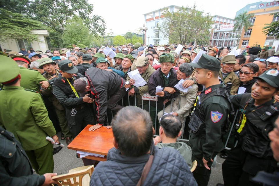 Một người trèo qua hàng rào chen lấn tới chỗ làm thủ tục đăng ký vé.