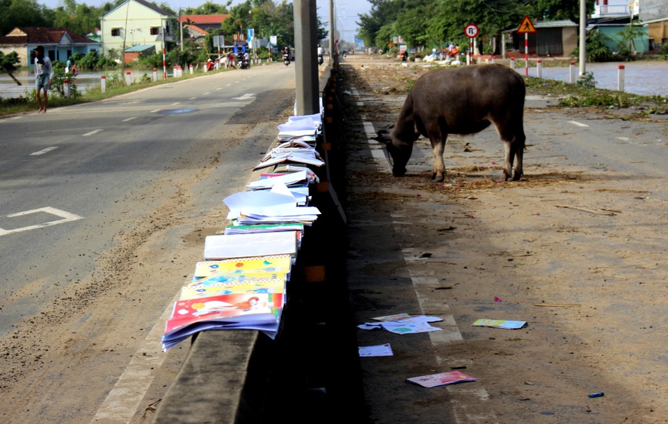 Quốc lộ 1 đã thông xe, người dân dọn dẹp nhà cửa sau lũ - 3 Người dân mang đồ đạc, sách vở bị ngập lụt ra ngoài quốc lộ 1 phơi sau khi nước rút