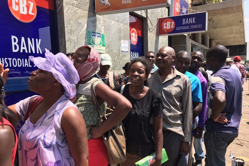 Quá thiếu lương thực, đồ dùng, dân Zimbabwe cứ thấy xếp hàng là “nhảy” vào - 1 Người dân Zimbabwe xếp hàng để được rút tiền tại ngân hàng. (Nguồn: NPR)