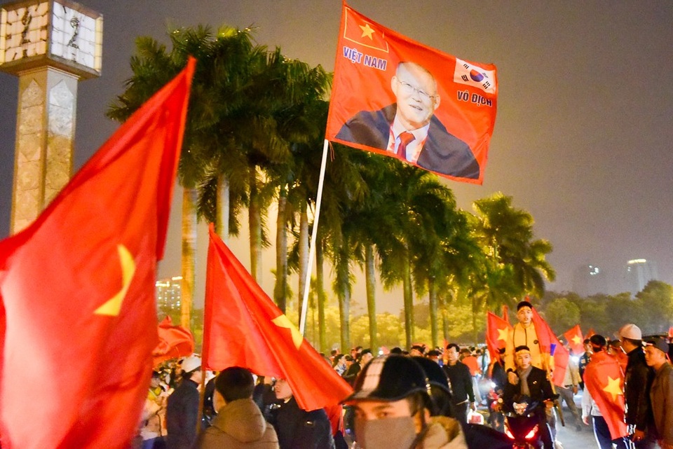 CĐV Việt Nam đốt pháo sáng ăn mừng trước SVĐ Mỹ Đình - 8 Một cổ động viên cầm lá cờ có hình HLV Park Hang Seo chạy dọc tuyến đường.