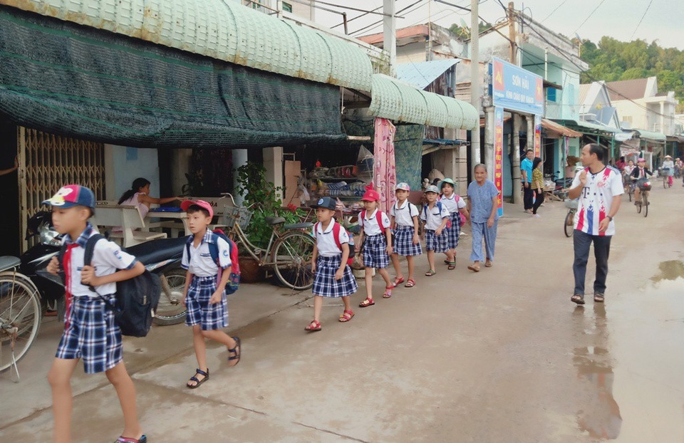 Cụ bà 81 tuổi gần 20 năm đưa đón học sinh từ nhà đến trường - 2 Các em học sinh di chuyển theo một hàng dọc, em học sinh học lớp lớn sẽ được bà Hai bố trí đứng đầu hàng, còn bà Hai là người đi sau cùng