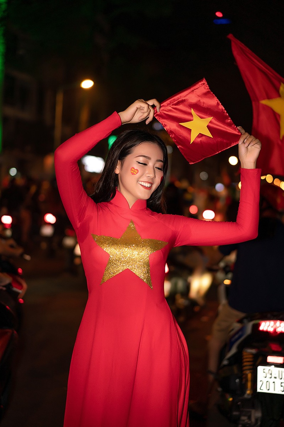 Á khôi Sinh viên mặc áo dài đỏ xuống đường mừng ĐT Việt Nam vô địch - 3 Hồng Hoa chia sẻ: “Mỗi lần Việt Nam thi đấu em đều theo dõi và cổ vũ. Đặc biệt là trận cầu lịch sử tối qua, em đã cùng một số bạn bè của mình cổ vũ tại phố đi bộ Bùi Viện. Không khí rất sôi nổi và em muốn hoà chung vào niềm vui chiến thắng ấy bằng cách mặc bộ áo dài cờ đỏ sao vàng. Là người con Việt Nam, khi khoác tà áo dài ấy, hô to “ Việt Nam vô địch!”. Cảm xúc thật tự hào khó tả!”.
