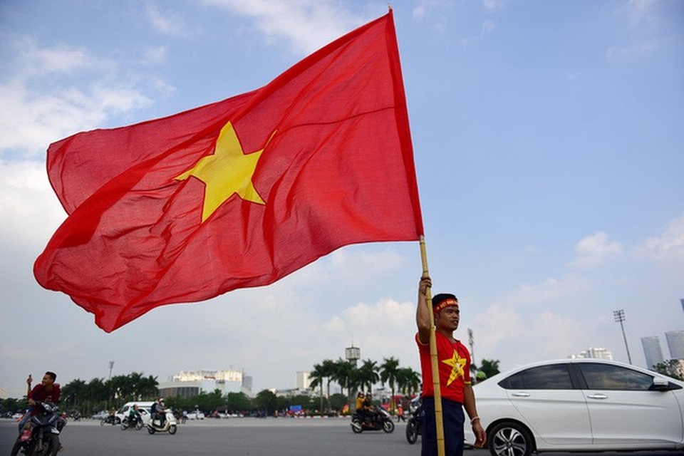 
Một cổ động viên chuẩn bị lá cờ Tổ quốc lớn để tham gia diễu hành cùng đoàn. ảnh: Toàn Vũ
