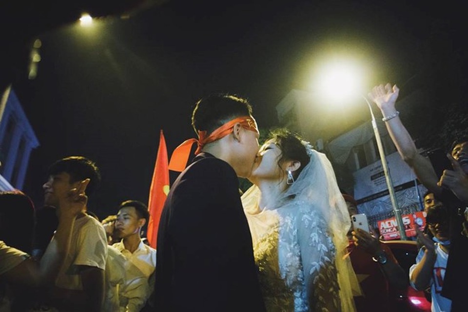 Cặp đôi “hoãn” chụp ảnh cưới, đi “bão” mừng chiến thắng của đội tuyển Việt Nam - 1 Trong rừng cờ đỏ, sao vàng cô dâu chú rể ngập tràn hạnh phúc. Ảnh: Hoàng Ken