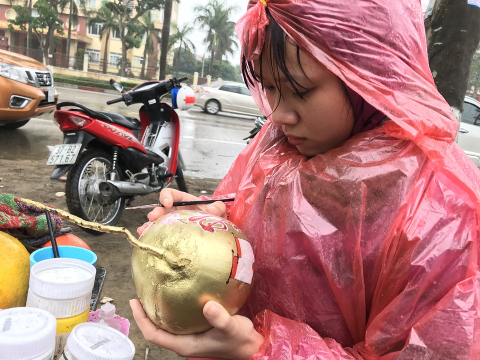 Người dân đội mưa, chịu rét ra tận lề đường “tiếp thị” sắc xuân - 11
Một cô gái đội mưa để tạo vẽ hình lên các loại hoa quả bán tết.