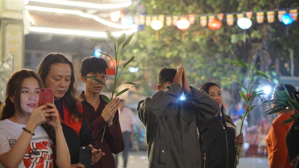 Người dân nô nức đi lễ chùa ngay sau thời khắc giao thừa - 2 Phật tử lễ Phật với cành lộc trên tay
