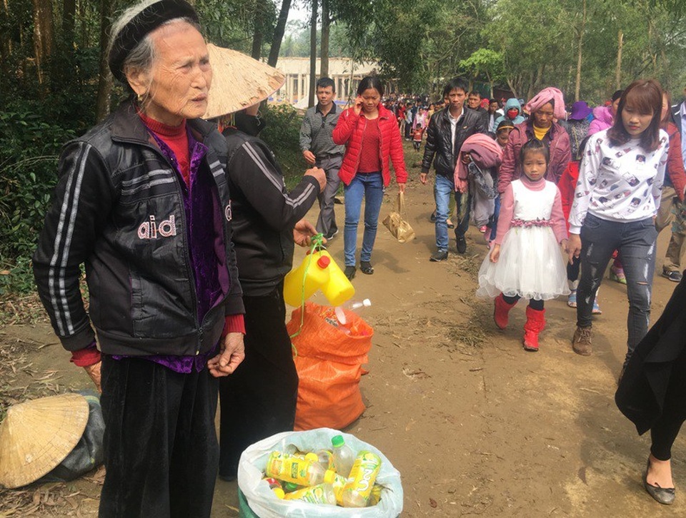 Cụ bà tranh thủ lấy chai lọ đến chùa bán cho người dân và du khách có nhu cầu mua để xin nước thánh.