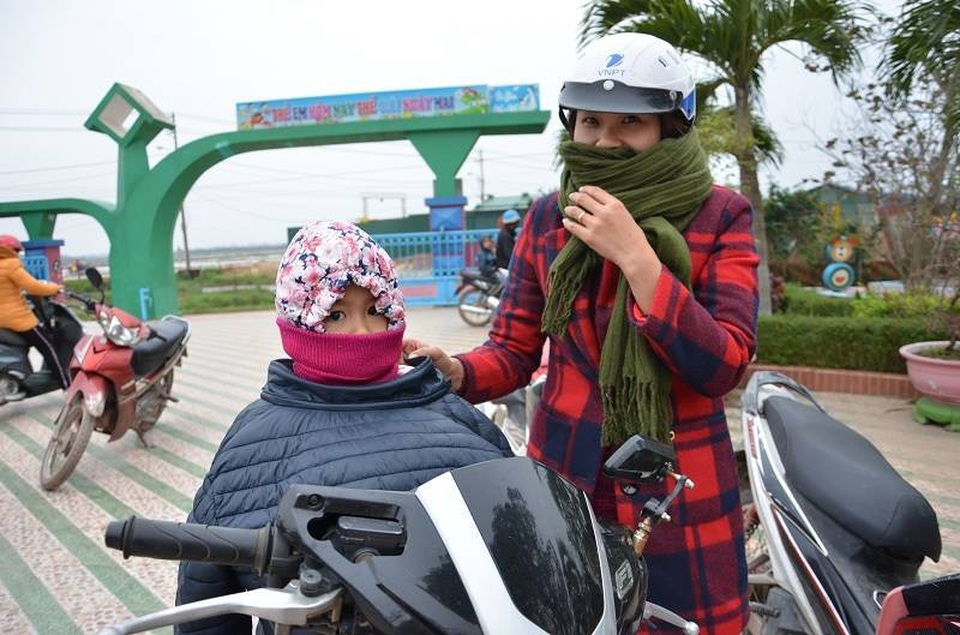 Trẻ em miền Trung hóa... ninja tới trường trong giá rét - 10 Một phụ huynh ở Trường Mầm non Đồng Phú, Tp Đồng Hới choàng cả áo người lớn giữ ấm cho con khi tới trường.