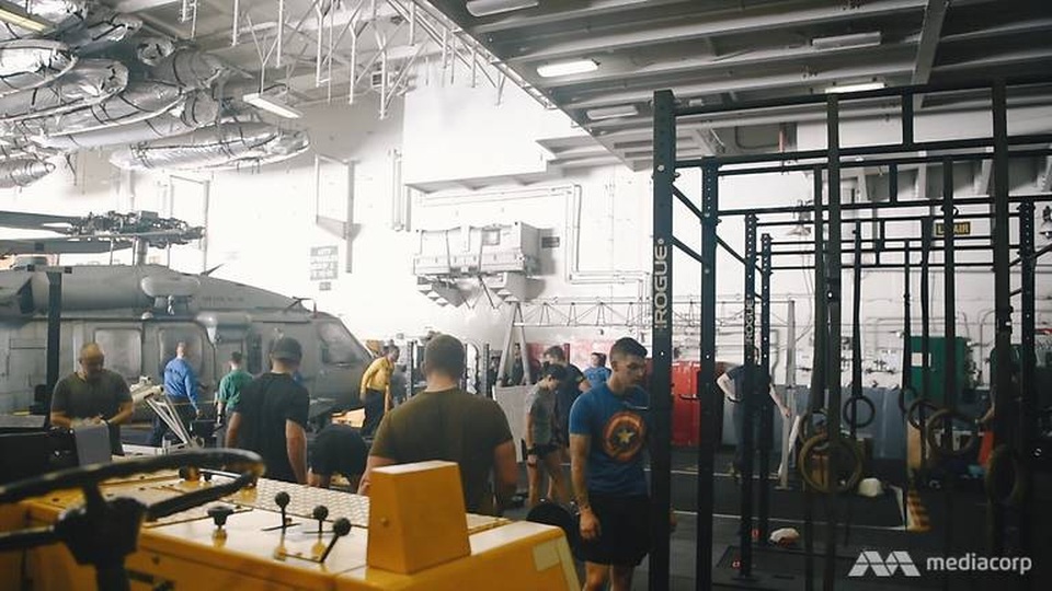 Cuộc sống trên “thành phố nổi” USS Carl Vinson vừa thăm Việt Nam - 5 Bên dưới boong tàu là một cuộc sống hoàn toàn khác của các thủy thủ. Trong khi một số người tập thể dục ở một góc của buồng chứa máy bay, các nhân viên bảo dưỡng máy bay vẫn bận rộn với công việc của họ. (Ảnh: Mediacorp)