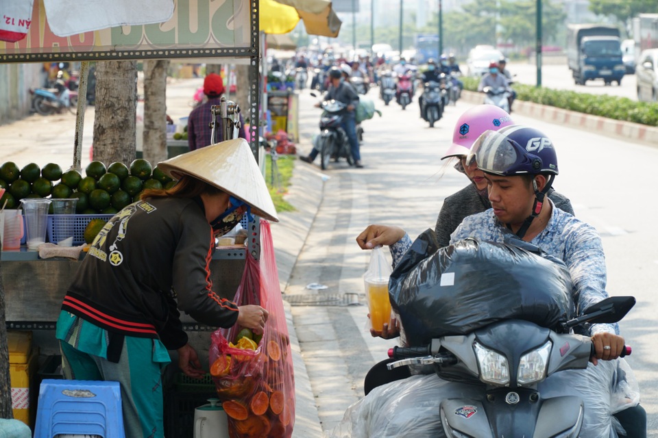 Sài Gòn nắng gay gắt, người dân xếp hàng chờ mua nước giải nhiệt - 9 
Hai vợ chồng chở hàng về Thủ Đức tranh thủ ghé vào ven đường mua 2 ly nước cam với giá 10 ngàn đồng/ly.