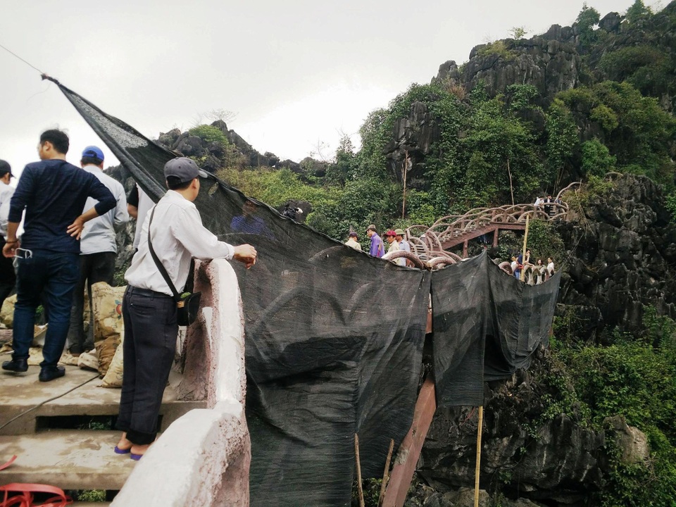 Chính thức tháo dỡ công trình “khủng” xâm hại di sản Tràng An - 2 Trước khi bắt đầu tháo dỡ, nơi bị phá bỏ được che kín bởi tấm bạt đen khổ lớn. Việc che tấm bạt là để ngăn không cho bê tông, xi măng, sắt thép rơi vãi xuống núi, tránh làm mất mỹ quan, xâm hại thêm vào di sản.
