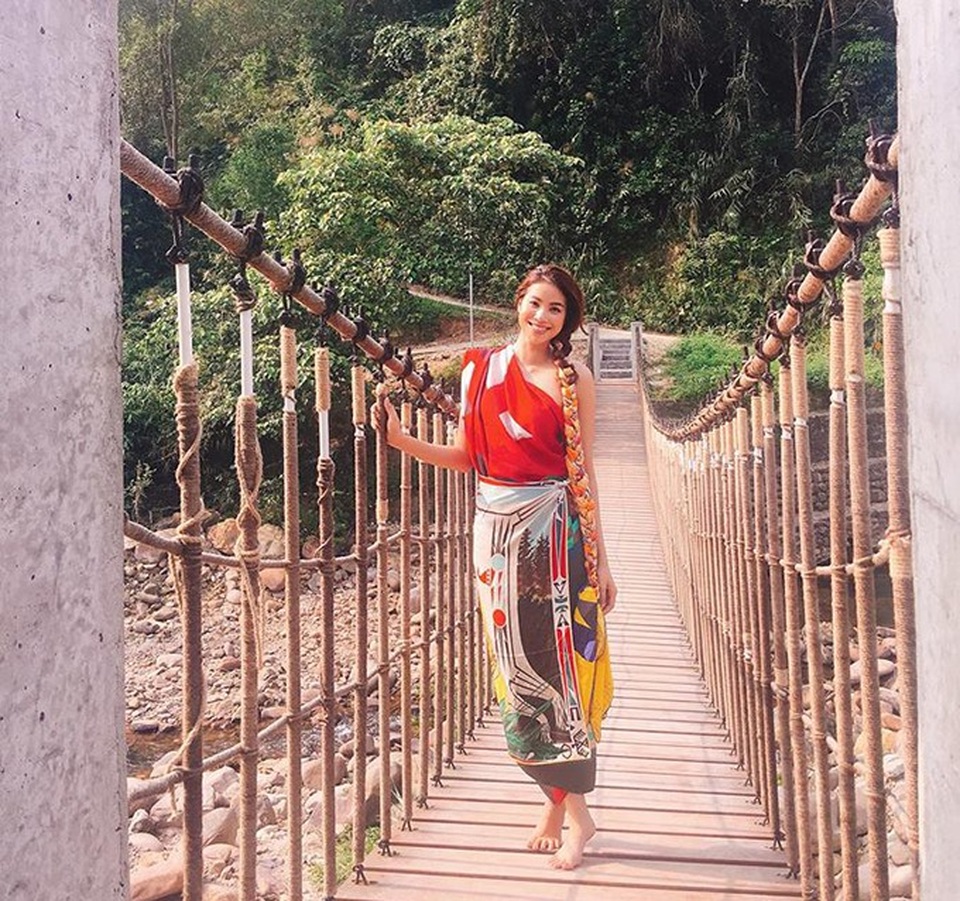 Hoa hậu Phạm Hương dùng khăn hàng hiệu làm váy quấn, đi chân trần lên cây cầu treo bắc qua sông ở Huế.