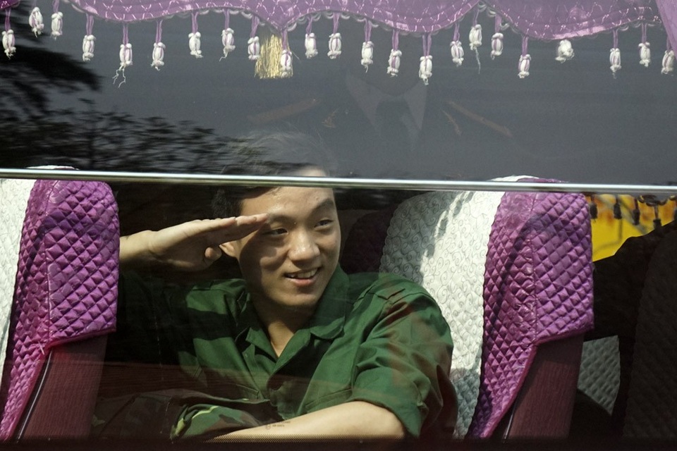 
Một tân binh rạng rỡ chào người thân khi đã yên vị trên xe.
