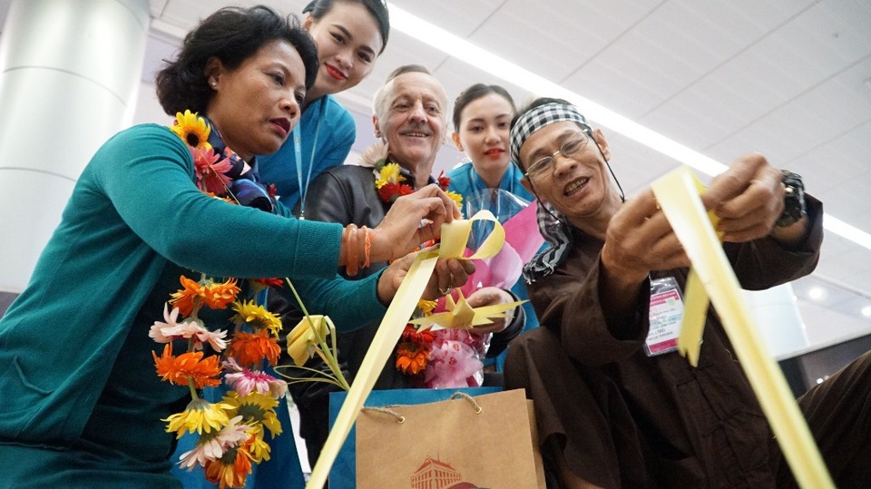 Bà Mbodj Camtam đang được nghệ nhân hướng dẫn gấp chú cào cào từ tàu lá