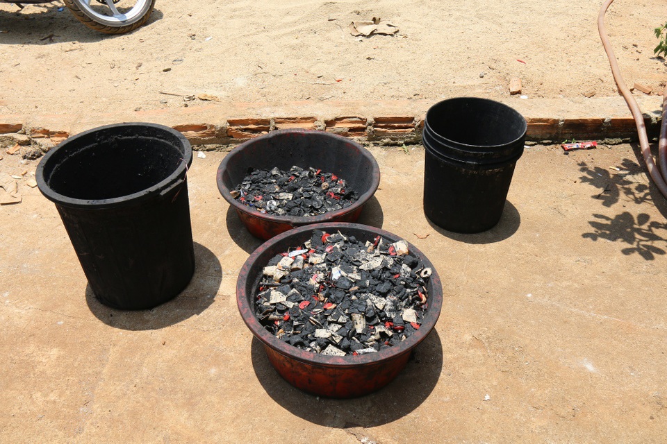 Một khu chứa nguyên liệu bao gồm vỏ cà phê, bột đá, bột pin con ó, nhiều thùng đựng nước màu đen, máy trộn và lò sấy.