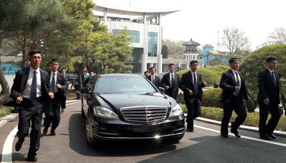 Khi xe tăng tốc, các vệ sĩ cũng tăng tốc theo. Họ đều mặc trang phục giống nhau là vest đen, sơ mi trắng, cà vạt xanh kẻ sọc và đeo huy hiệu trên ngực áo. (Ảnh: Yonhap)