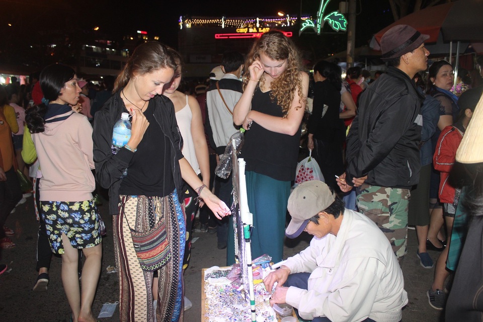 Ba vị khách nước ngoài đang lựa chọn mua những món đồ lưu niệm tại chợ đêm Đà Lạt