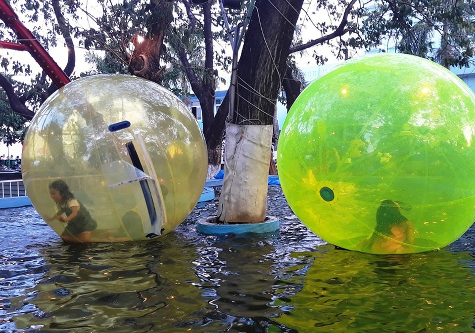 Nhiều em nhỏ thích thú với trò chơi mới khi chui vào bên trong quả bóng cầu lớn rồi bơm khí vào.
