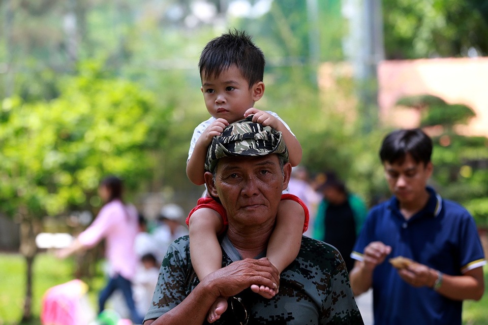 Em bé mướt mồ hôi được ông cõng lên vai thoát khỏi đám đông.