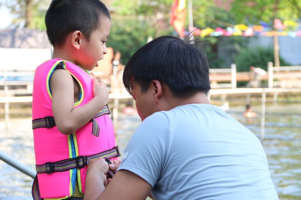 Trẻ thích thú với "bể bơi tự chế" từ ao làng ngoại thành Hà Nội - 7
Một em bé được bố mặc áo phao trước khi xuống ao tập bơi.
