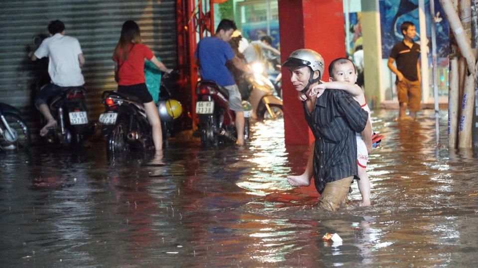 TPHCM: Mưa lớn kéo dài, nhiều tuyến đường ngập qua yên xe máy - 13 Cha cõng con lội cẩn thận từng bước qua dòng nước