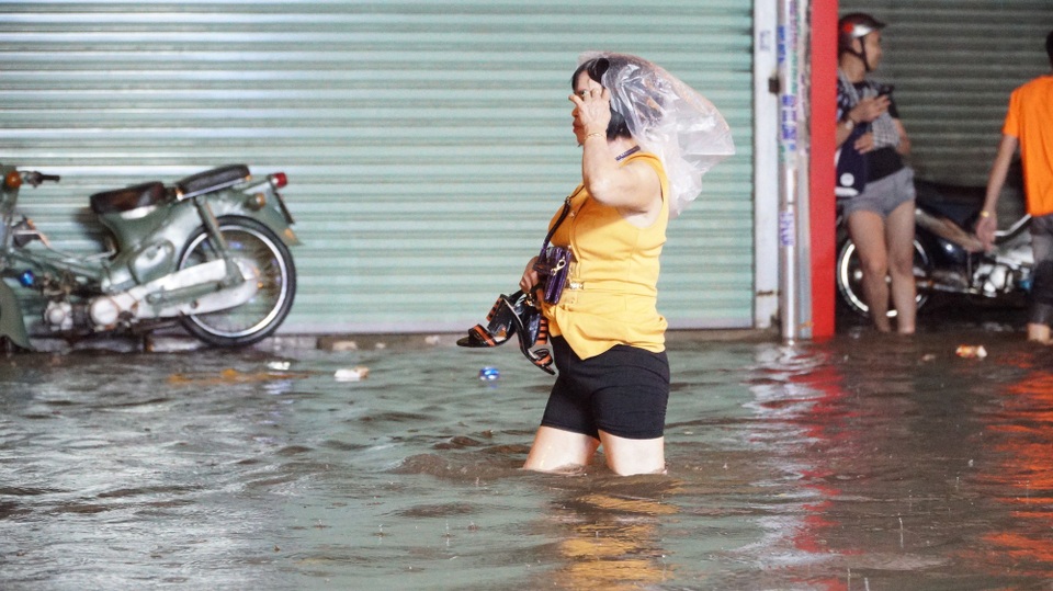 TPHCM: Mưa lớn kéo dài, nhiều tuyến đường ngập qua yên xe máy - 15 Một phụ nữ xách guốc, đội bịch nilong che mưa lội nước về nhà