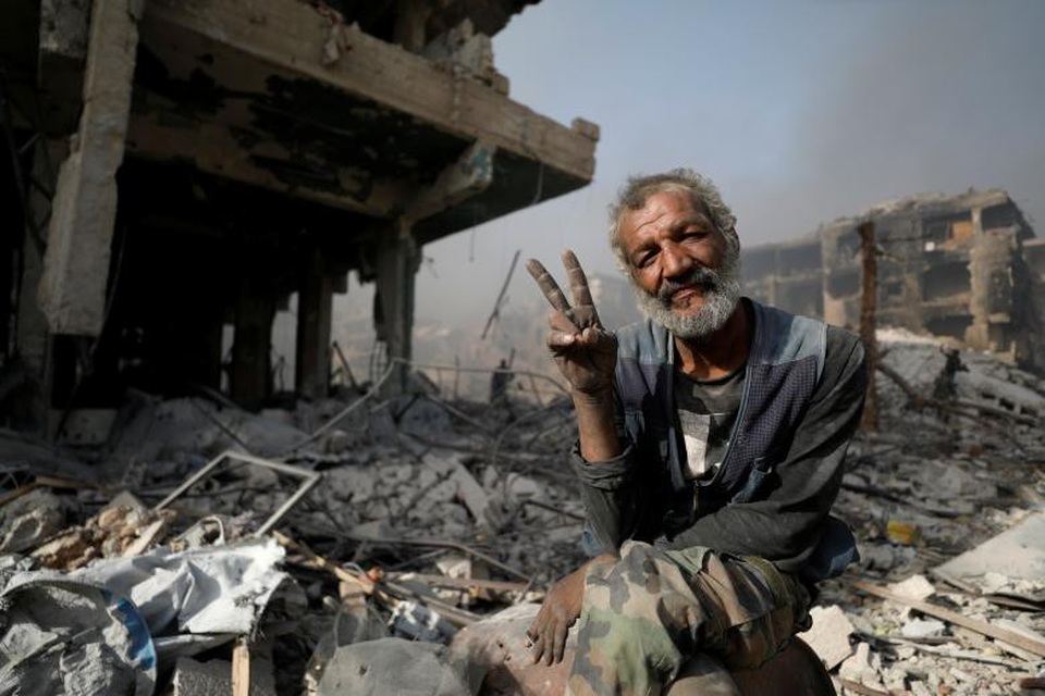 Thủ đô Syria hoang tàn sau 7 năm chìm trong bom đạn - 1 Quân đội Syria đã giành quyền kiểm soát thủ đô Damascus lần đầu tiên trong 7 năm nội chiến, sau khi đẩy lùi các tay súng phiến quân thuộc tổ chức Nhà nước Hồi giáo tự xưng (IS) ra khỏi khu vực phía nam Damascus. Trong ảnh: Một người đàn ông ngồi trên đống đổ nát của ngôi nhà bị tàn phá trong các cuộc giao tranh ở vùng al-Hajar al-Aswad, ngoại ô Damascus hôm 21/5.