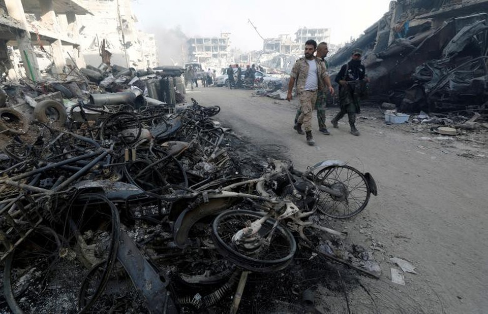 Thủ đô Syria hoang tàn sau 7 năm chìm trong bom đạn - 8 Xe bị thiêu cháy chất thành đống ở hai bên đường tại al-Hajar al-Aswad.