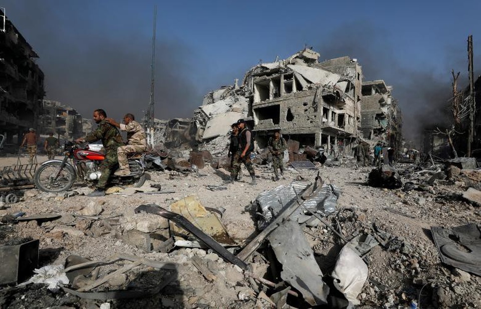 Thủ đô Syria hoang tàn sau 7 năm chìm trong bom đạn - 2 Các lực lượng ủng hộ chính phủ Syria đã chiến đấu trong nhiều tuần để giành lại quyền kiểm soát al-Hajar al-Aswad và các vùng lân cận khỏi sự chiếm đóng của IS. Trong ảnh: Các binh sĩ quân đội Syria lái xe qua khu vực đổ nát al-Hajar al-Aswad.