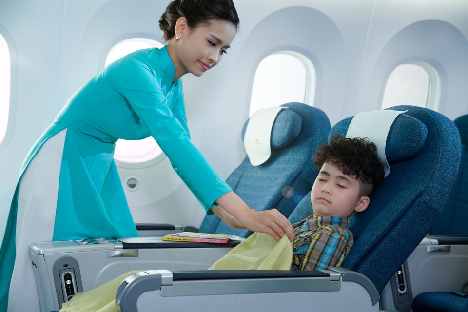 Hàng không quốc gia dành nhiều quà tặng cho các em nhỏ dịp 1/6 - 2 Tiếp viên VNA chăm sóc một hành khách nhỏ tuổi trên máy bay