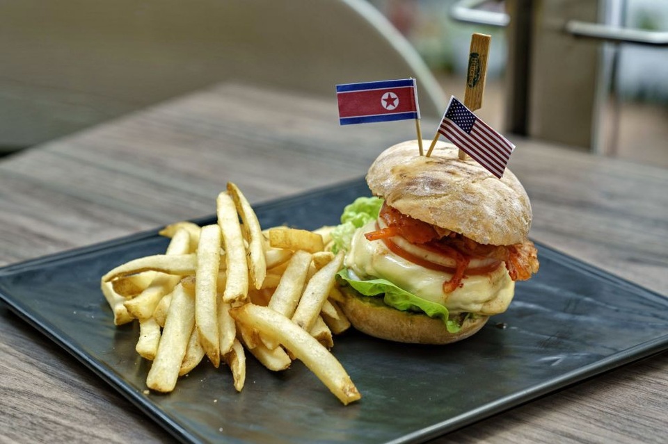 Hình ảnh thú vị bên lề hội nghị thượng đỉnh Mỹ - Triều - 1 Món bánh “Cowboy Kimchi Burger” được phục vụ tại một nhà hàng ở Singapore trước thềm hội nghị thượng đỉnh Mỹ - Triều. Đây là món ăn kết hợp giữa hai “đặc sản” của Mỹ và Triều Tiên với điểm nhấn là hai lá cờ Mỹ - Triều thu nhỏ.