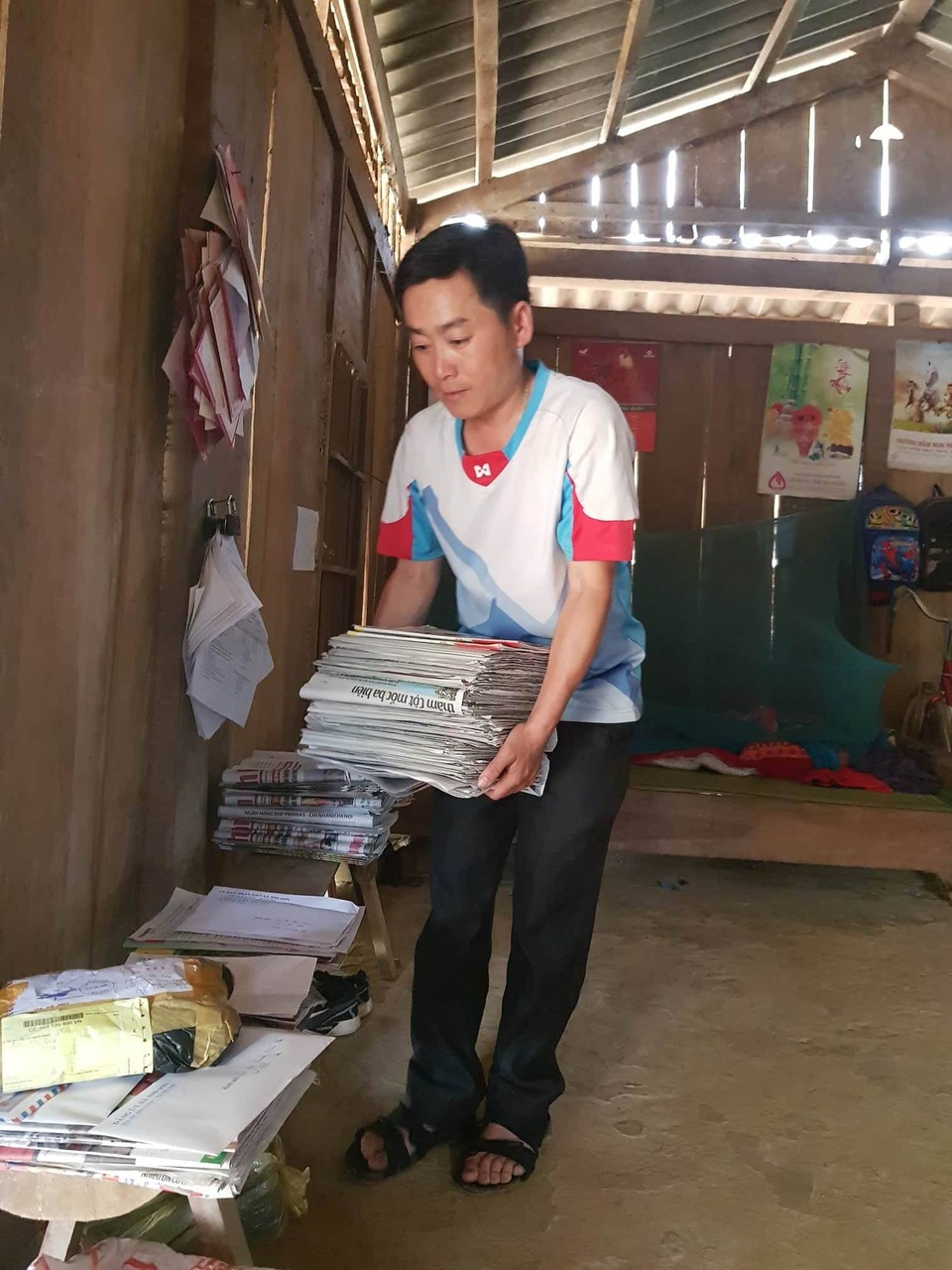 Lặng lẽ công việc của anh bưu tá vùng cao - 1 Anh Di đang chuẩn bị công việc mang thư tín, báo chí về bản làng.